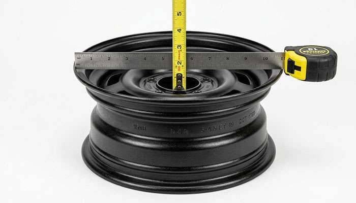 Measuring backspacing on a 15x8 steel off-road wheel with a straightedge and tape measure