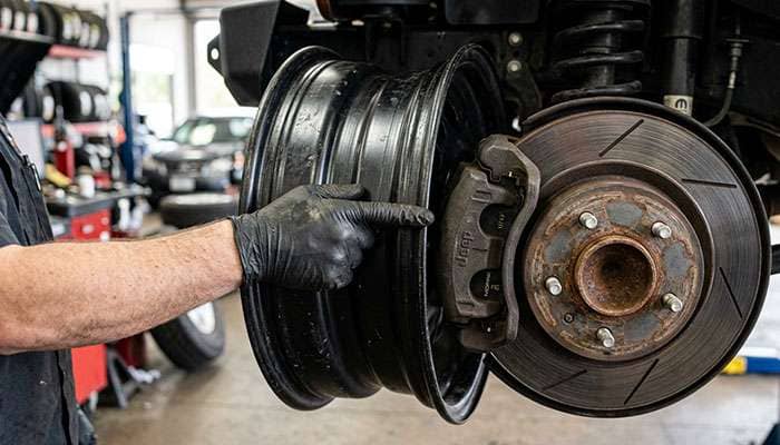 16-inch steel wheel held against a large Jeep front brake caliper to check barrel and spoke clearance