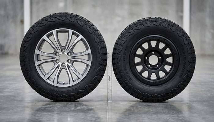 Comparison of 20-inch silver wheel and 18-inch black wheel with Cooper Discoverer tires on concrete floor
