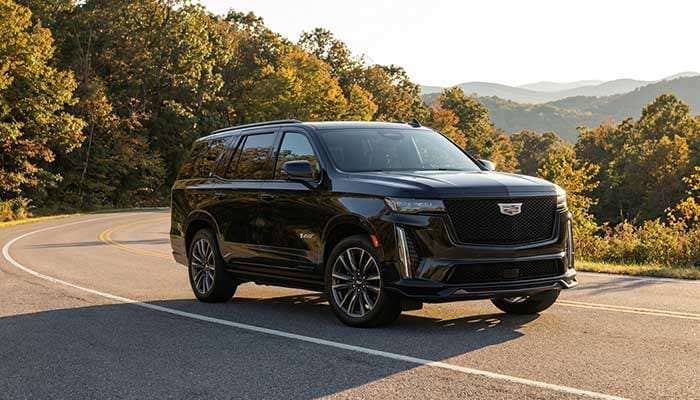 2023 Cadillac Escalade-V luxury SUV parked outdoors with trees in the background and review text overlay