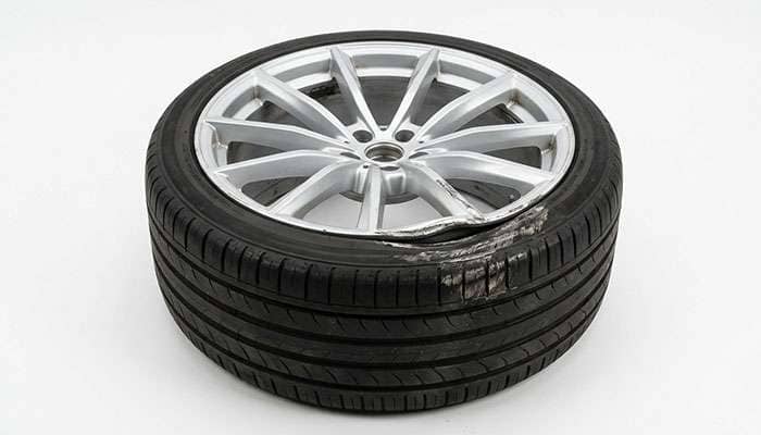 21 inch alloy wheel with a bent rim lip and scuffed low profile tire sidewall