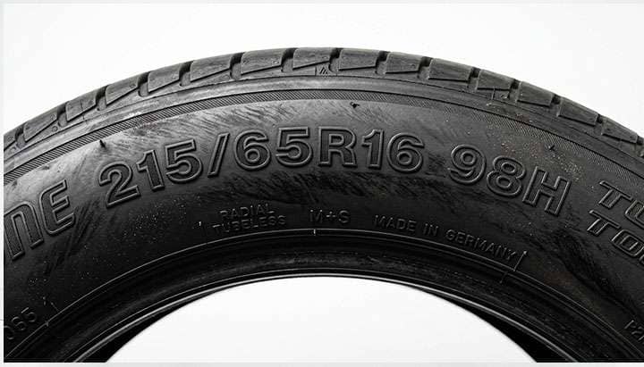 Close-up of a tire sidewall showing the 215 65R16 size marking in raised lettering