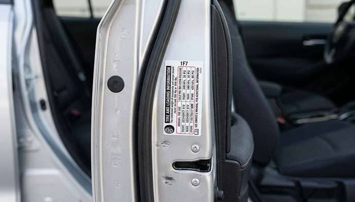Driver door jamb tire placard showing 225/50R18 tire size and load index on a modern sedan