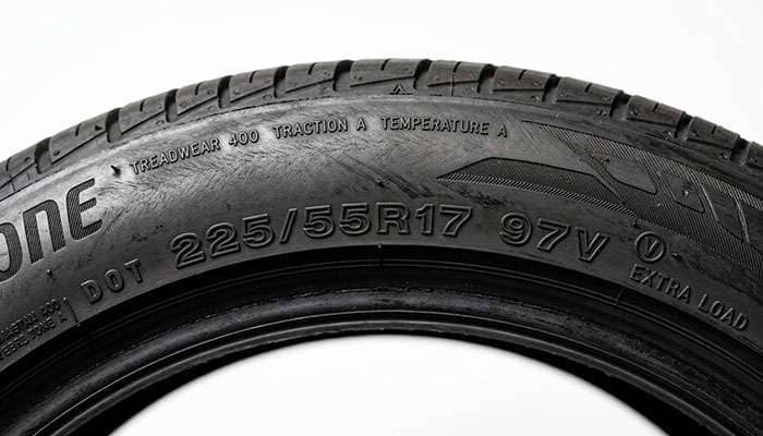 Close-up of a tire sidewall showing the 225/55R17 size and service description markings