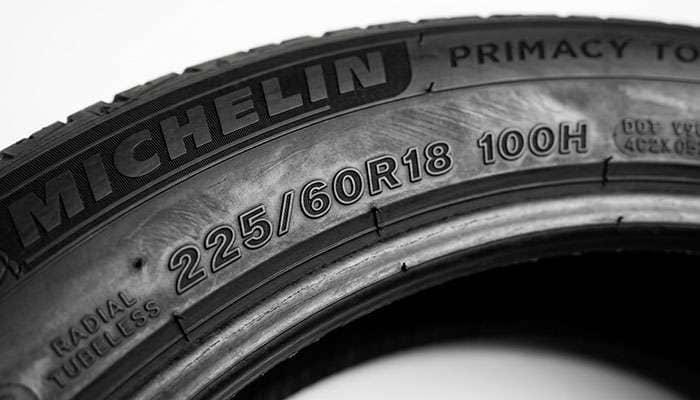 Close-up of a tire sidewall showing the raised size code, load index, and speed rating markings