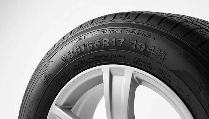 Close-up of a 235/65R17 tire sidewall showing the 104H load index and speed rating marking