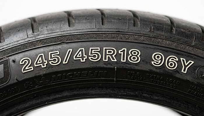 Close-up of a tire sidewall showing the 245/45R18 size and speed rating markings