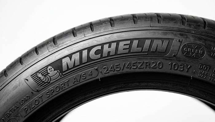 Close-up of a tire sidewall showing the 245/45R20 size marking with load index and speed rating stamped beside it