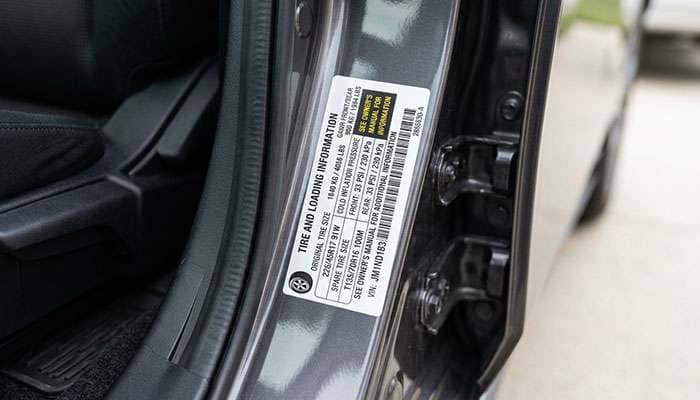 Driver door jamb tire placard showing tire size, load index and cold inflation pressure