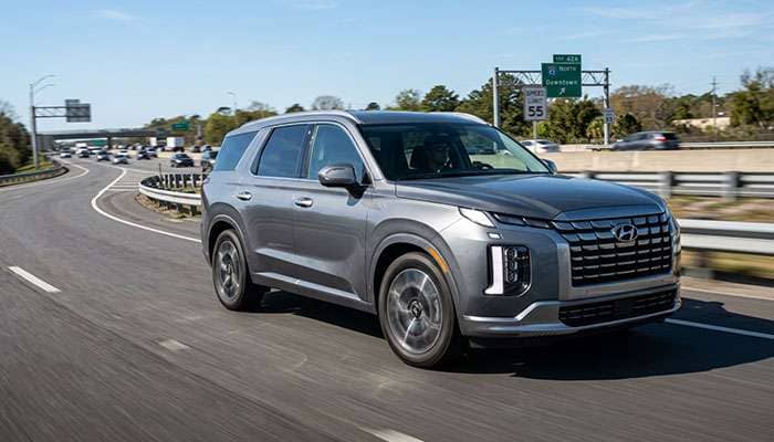 Three-row SUV on a highway on-ramp with 18-inch wheels and touring tires