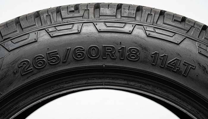 Close-up of a truck tire sidewall showing the 265/60R18 size marking and the load index and speed rating service description