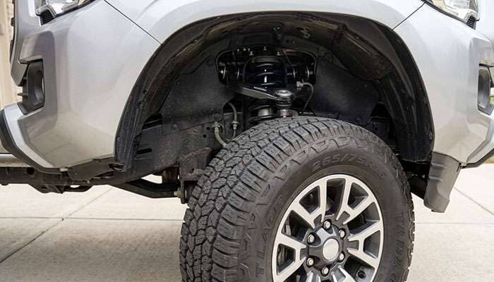 265/75R16 all-terrain tire at full steering lock close to the upper control arm and fender liner of a pickup