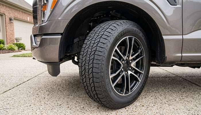 LT275/65R20 all-terrain tire on a half-ton pickup at full steering lock close to the front fender liner and bumper valance