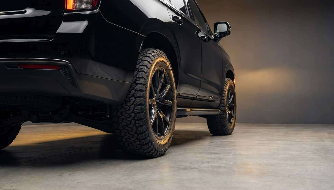 Close-up of a black SUV showcasing rugged 285 45R22 tires in a studio setting with warm lighting