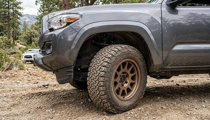 Midsize pickup truck front wheel well with a 285/70R17 all-terrain tire on a 17-inch aftermarket wheel turned to full steering lock