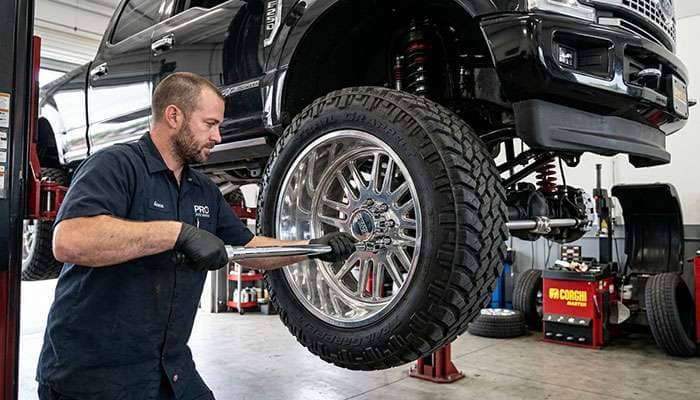 Technician torquing lug nuts on a large diameter wheel in a service bay