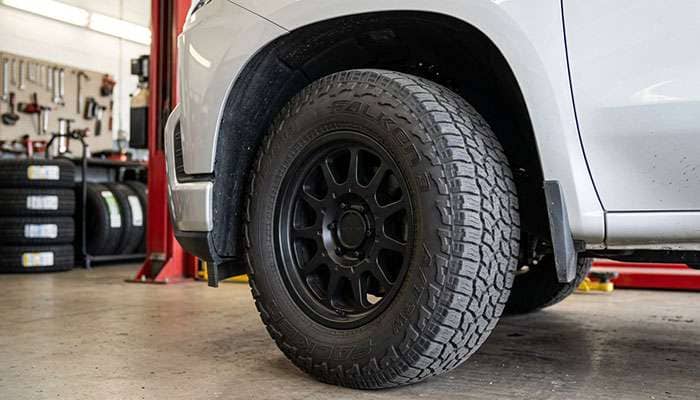 Half-ton pickup front wheel turned to full lock showing a 33-inch all-terrain tire close to the plastic fender liner