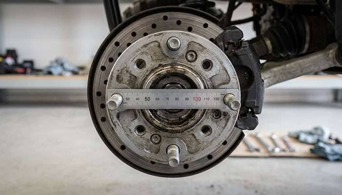 Four lug ATV wheel hub with a ruler measuring center to center across opposing studs