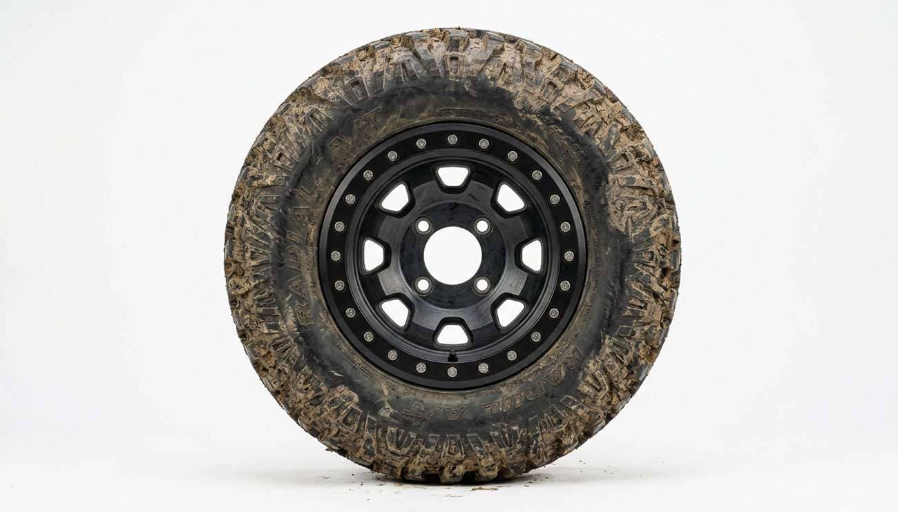 Four lug UTV wheel with a knobby off road tire mounted, photographed against a clean white seamless backdrop
