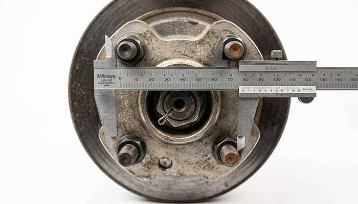 Calipers spanning two opposite studs on a four lug UTV hub to measure the bolt circle