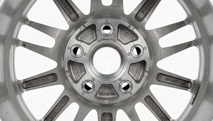 Close-up of a 5x100 bolt pattern wheel showing five lug holes on a 100 millimeter circle