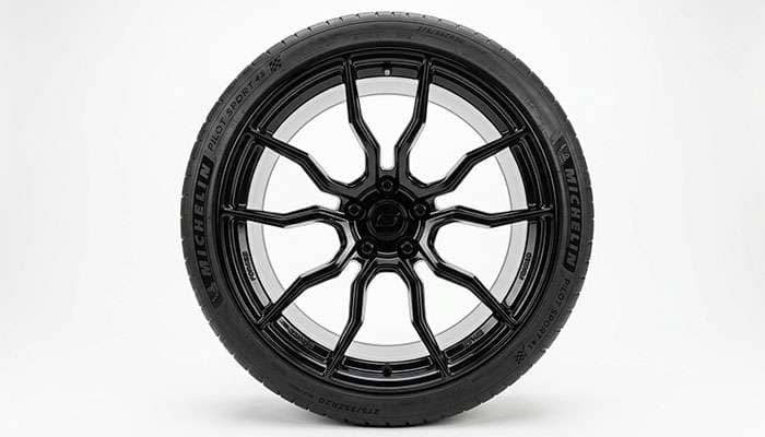 Modern American muscle sedan aftermarket wheel with a 5x115 bolt pattern and concave spoke design, on a clean white studio backdrop