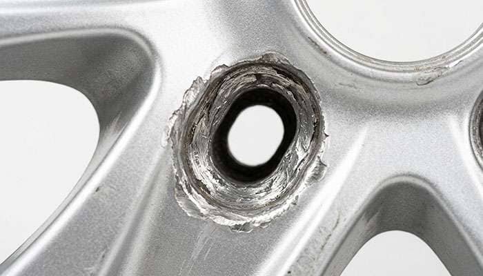Close-up of a wheel lug hole that has been elongated and worn oval from being mounted on the wrong bolt pattern