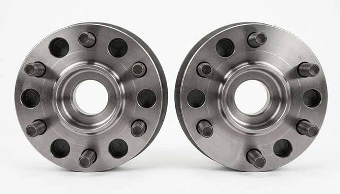 Two six lug wheel hubs side by side showing the small difference in bolt circle diameter between a narrower and a wider pattern