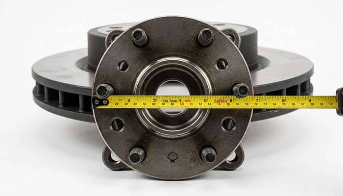 Wheel hub with six studs arranged in a circle, showing how a six-lug bolt pattern is measured