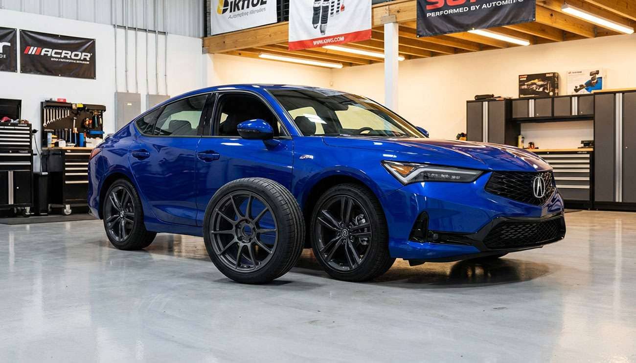 Blue Acura Integra sedan in a garage next to a detached aftermarket wheel and tire on the floor