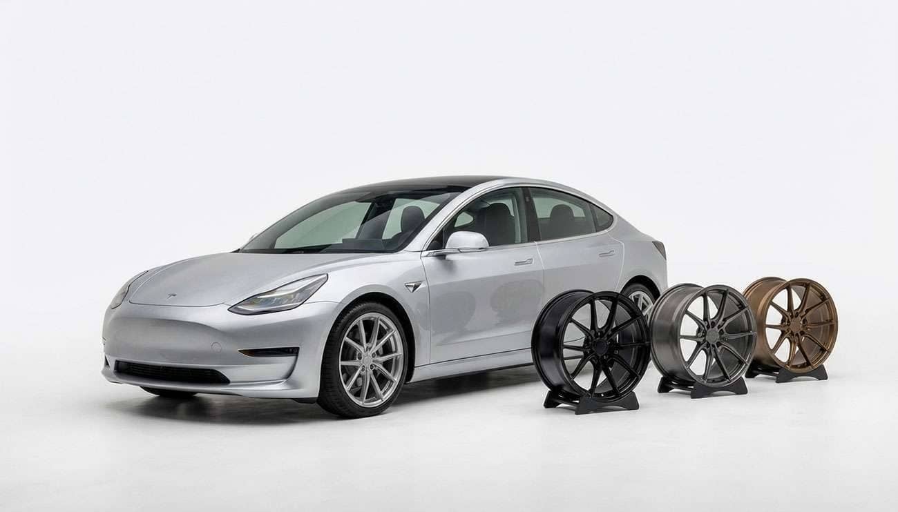 Silver Tesla Model 3 next to a display of three aftermarket wheels in black, gunmetal, and bronze finishes