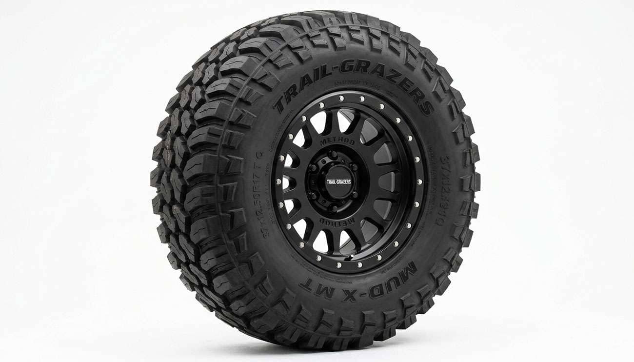 Close-up of an aggressive mud-terrain off-road tire with deep tread lugs and prominent sidewall biters on a clean white studio backdrop