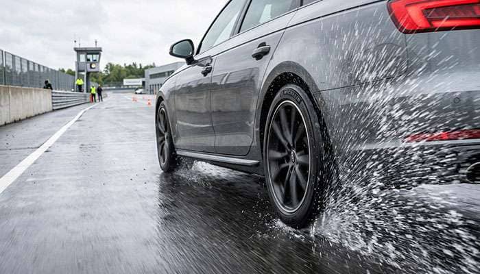 All-season tire performance testing in wet conditions showing water spray patterns and road contact