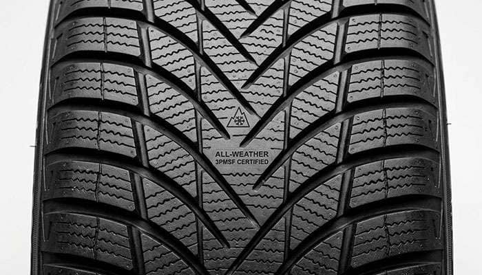 Close-up of all-weather SUV tire tread showing 3PMSF-certified siping pattern and directional V-formation design