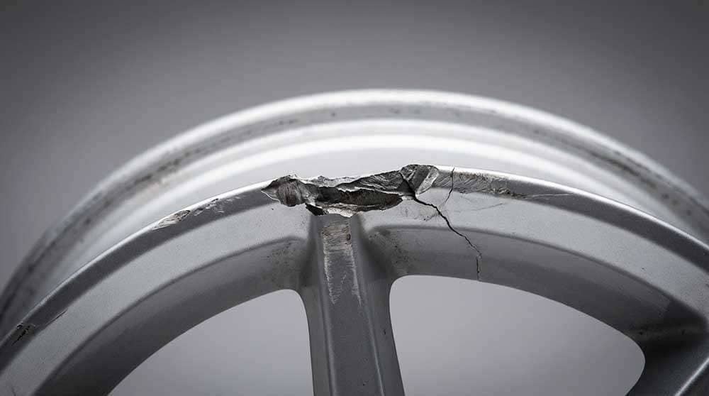 Close-up of an alloy wheel showing significant damage with a large chip on the rim edge