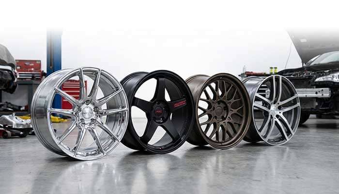 Four different styles of car wheels displayed in a workshop setting for a 2025 guide on wheel types