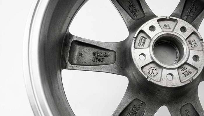 Close-up of cast markings on the back of an alloy wheel showing size, offset, load rating, and test marks