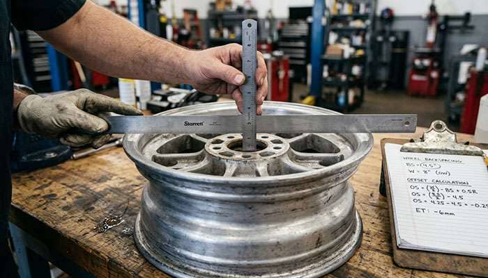 using a straight edge across classic car wheel to measure backspacing and convert to offset