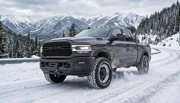 Pickup truck fitted with Mickey Thompson Baja Boss A/T tires driving on a snow covered mountain road
