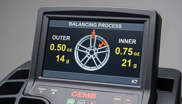 Wheel balancer display screen showing imbalance readout with counterweight placement instructions