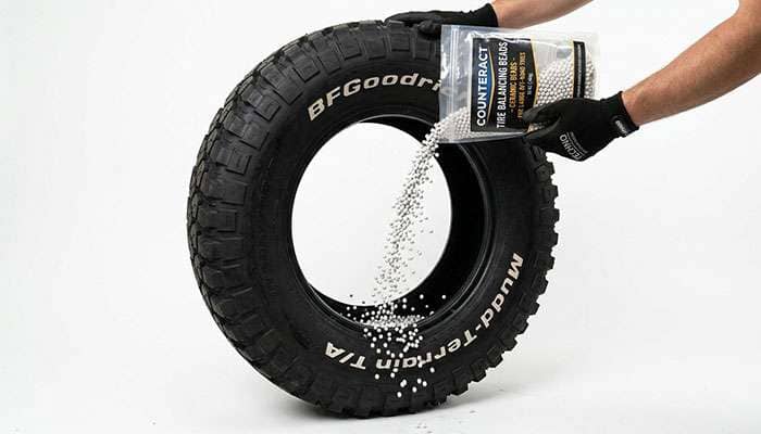 Ceramic balancing beads being poured into an off-road tire before mounting