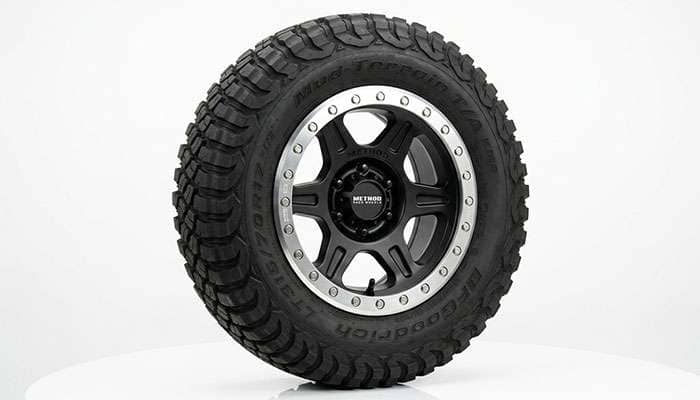 Beadlock off-road pickup truck wheel with a bolted outer ring on a clean white studio backdrop