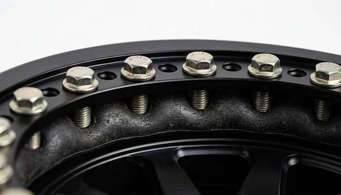 Close-up of a beadlock wheel outer ring with hex bolts clamping the tire bead