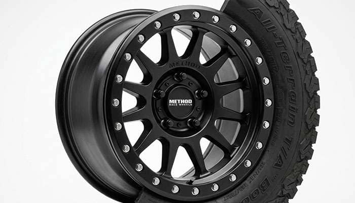An off-road beadlock wheel with a visible clamping ring on a clean white studio backdrop