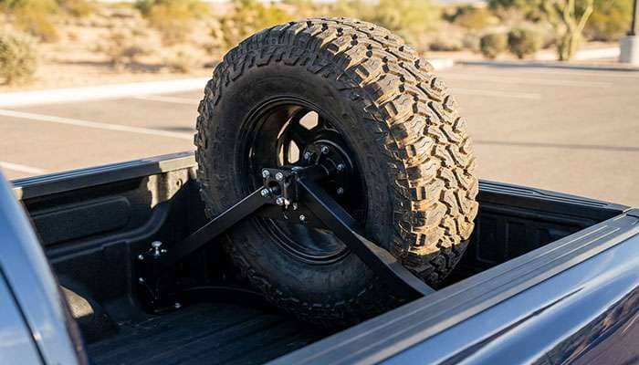 Rough Country bed mount spare tire carrier securely holding a large off-road tire in a truck bed