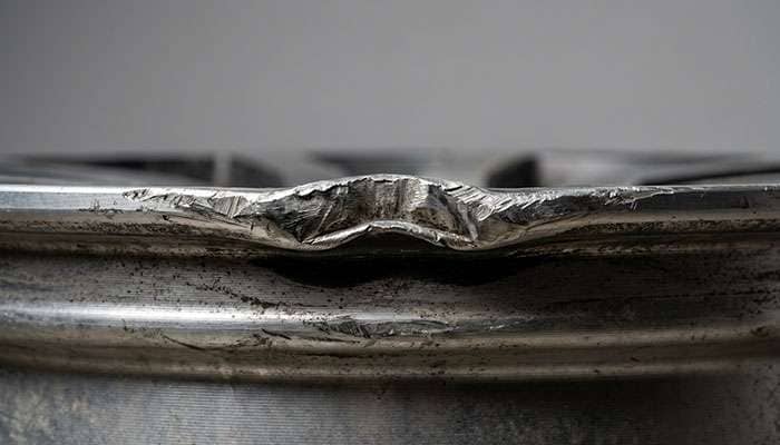 Close-up of bent truck rim edge showing deformation from pothole or curb impact