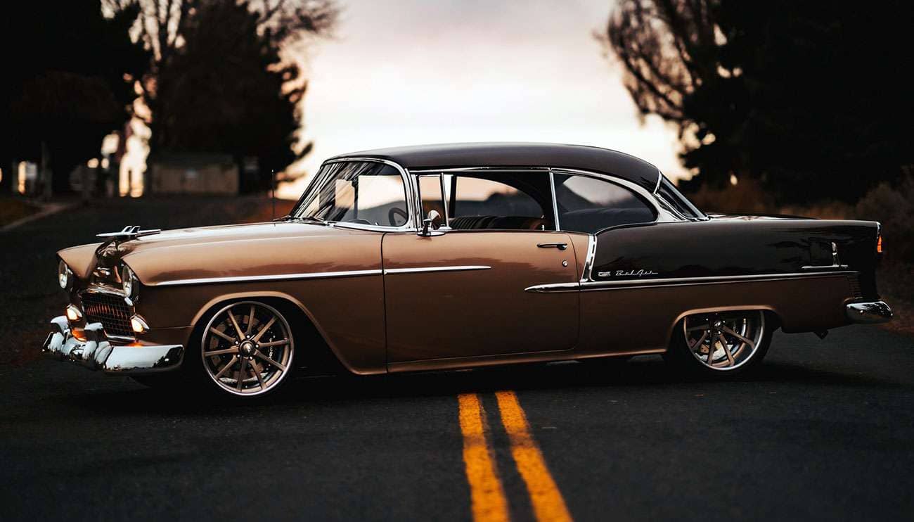 Black sports car with polished Billet Specialties wheels in a garage with wheel displays in the background