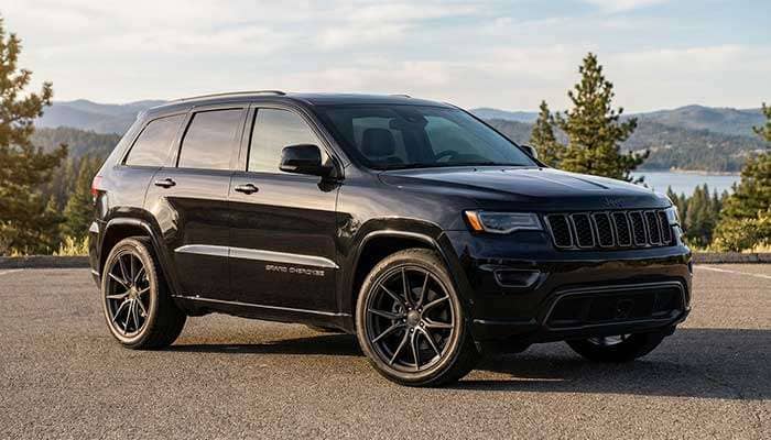 Black Jeep Grand Cherokee parked outdoors showcasing large custom black wheels and a sleek, modern design
