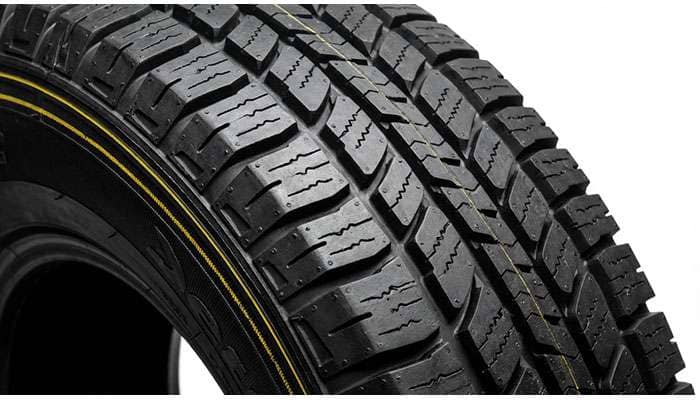 Close-up of a new black car tire showing detailed tread patterns and a yellow stripe along the circumference