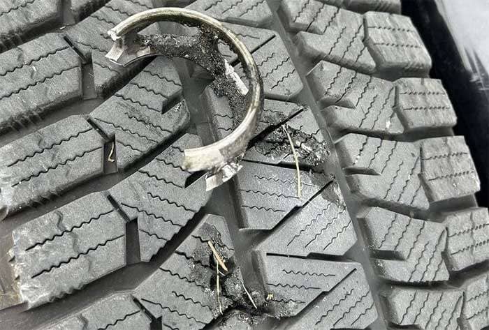 Close-up of a Bridgestone Blizzak WS90 winter tire tread with debris and minor damage visible in the grooves
